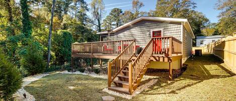 Une cabane à un seul étage, dotée d’une terrasse en bois et d’un escalier menant à une porte rouge.