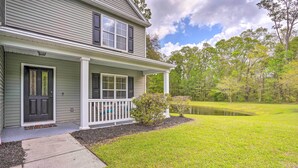 A two-story house with a front porch, a small pond, and a grassy yard. - Summerville Family Home ~ 20 Mi to Charleston (Summerville)