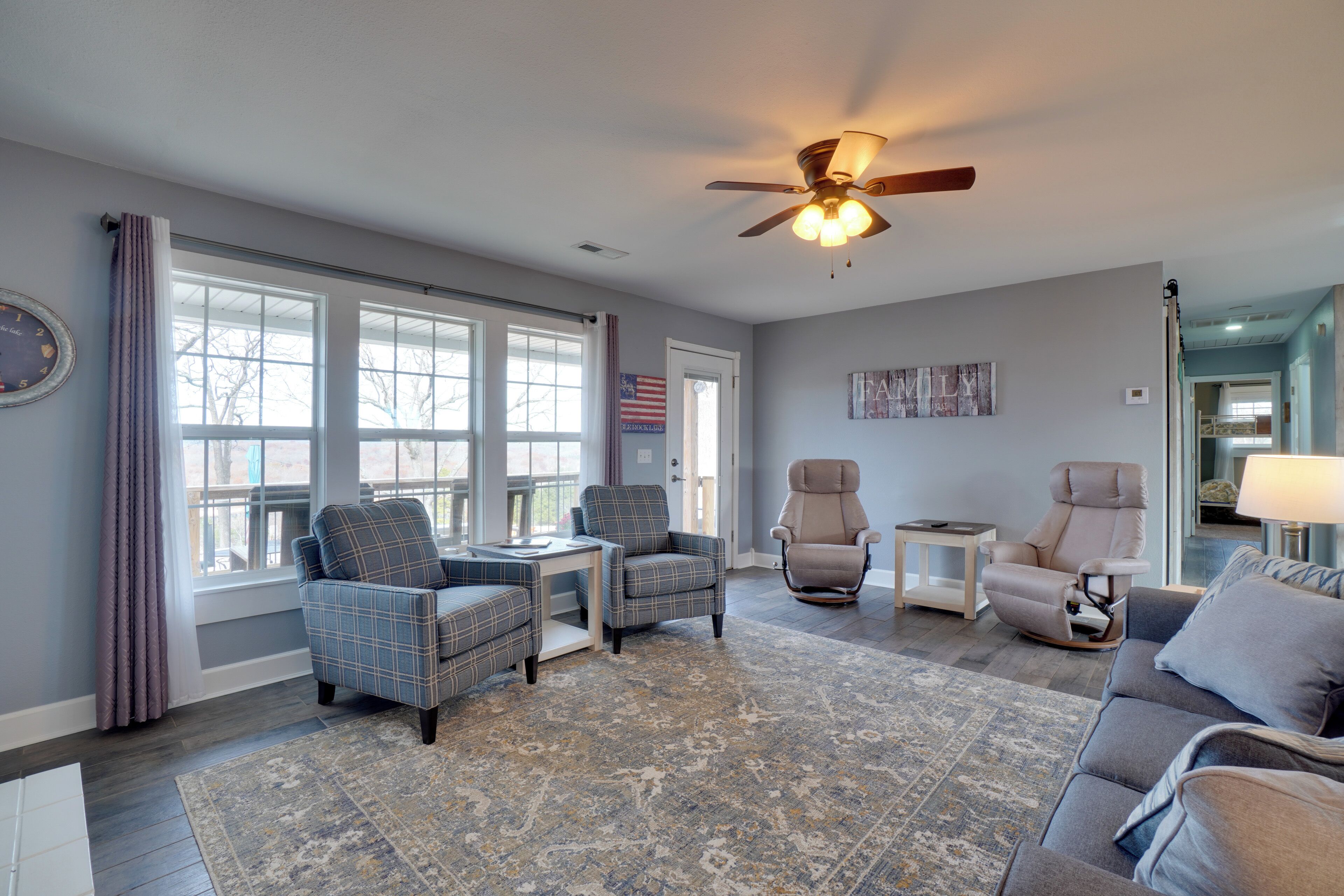 A living room with a ceiling fan, two armchairs, a sofa, a coffee table, and a rug.