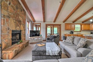 A living room with a stone fireplace, a television, and a grey sofa. - Table Rock Lake Getaway w/ Fire Pit, Deck & Grill! (Golden)