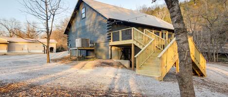 A log cabin with a wooden staircase leading to a deck.