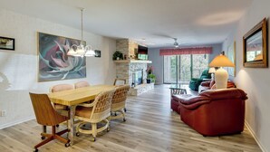 A modern living room with a dining area, a fireplace, and a large window. - Tranquil Osage Beach Condo w/ Waterfront Decks! (Osage Beach)