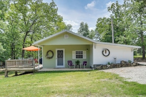 A single-story house with a porch, a wreath on the door, and two chairs outside.