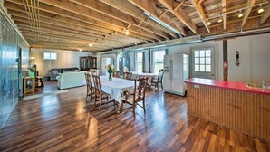 A spacious kitchen with wooden flooring, a dining area with a table and chairs, and a bar counter. - Updated Berger Cottage w/ Pool, on a Private Farm! (Berger)