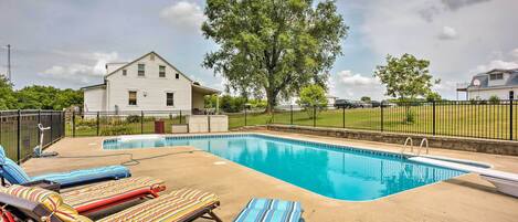 A swimming pool with lounge chairs and a house in the background.
