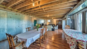 A spacious dining area with wooden tables and chairs, a kitchen area with appliances, and a rustic ceiling. - Updated Berger Cottage w/ Pool, on a Private Farm! (Berger)