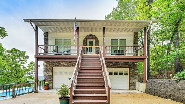 Une maison à deux étages avec un porche à l’avant, un escalier, une piscine et un garage.