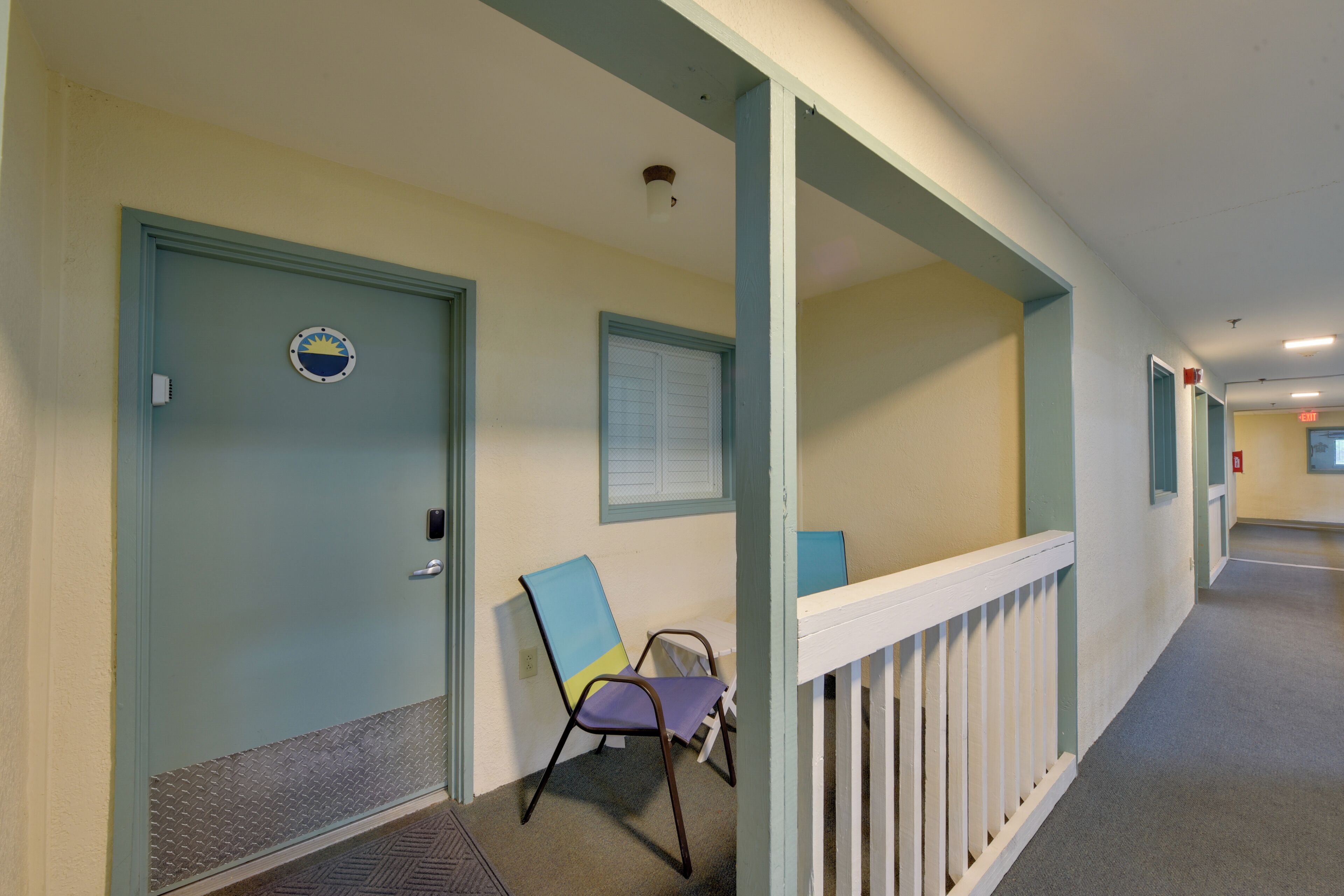 A hallway with a door, a chair, and a railing.