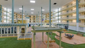 A multi-level hotel interior with a central atrium, balconies, and outdoor seating areas.