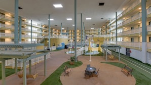 A multi-story hotel interior with balconies, a central courtyard, and a pool area.