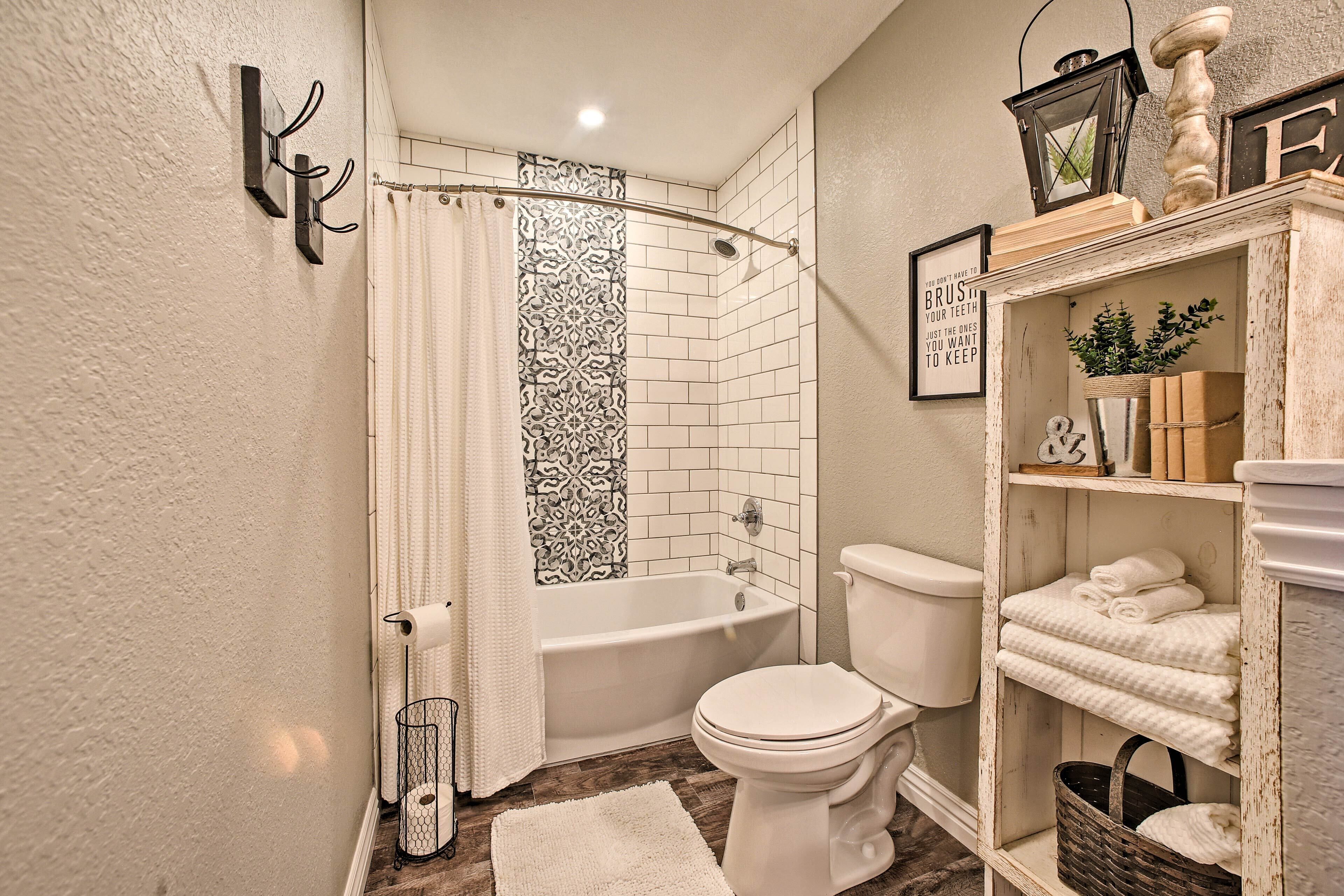 A bathroom with a bathtub, toilet, and a shelf with towels.