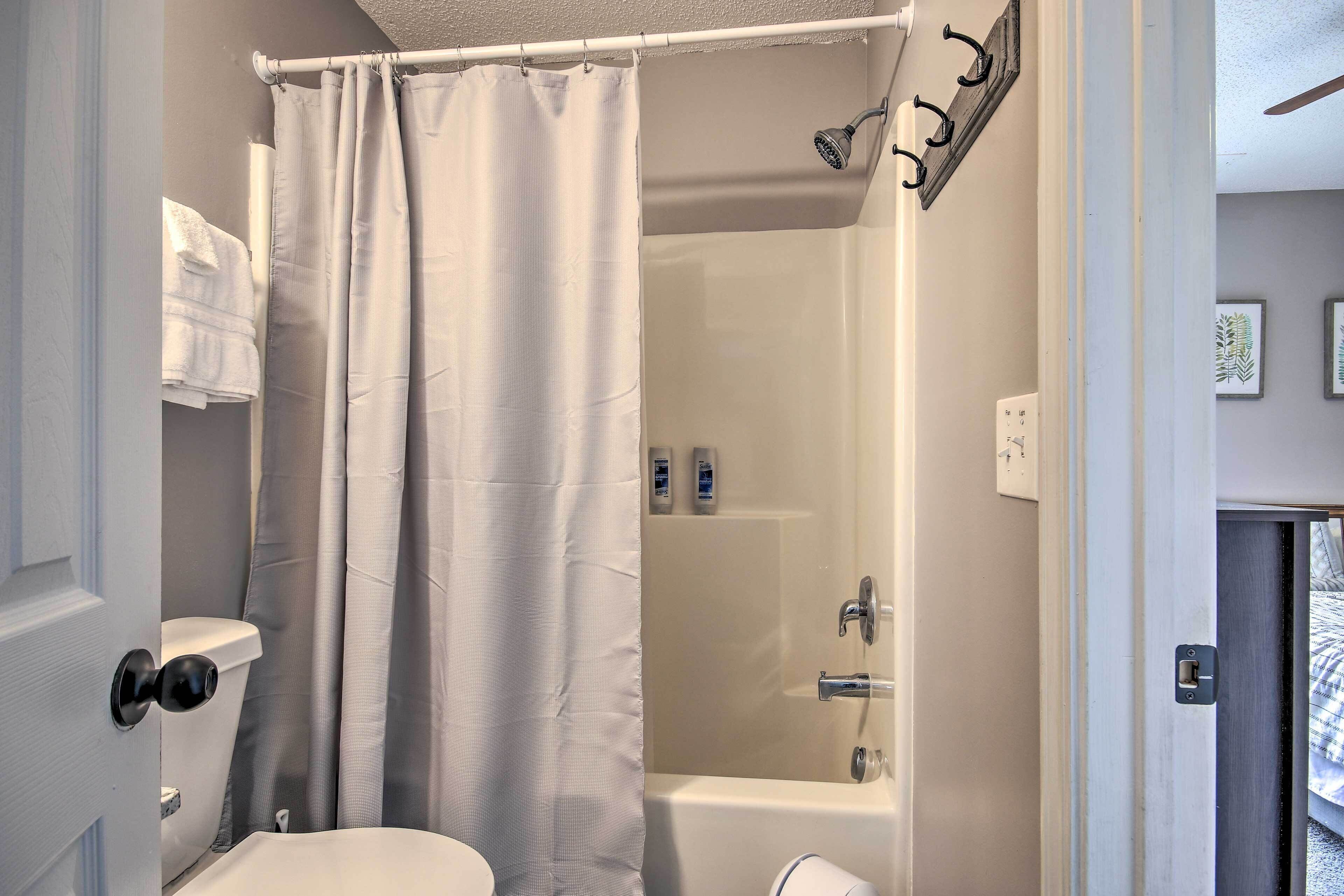 Un baño con ducha, inodoro y perchero.