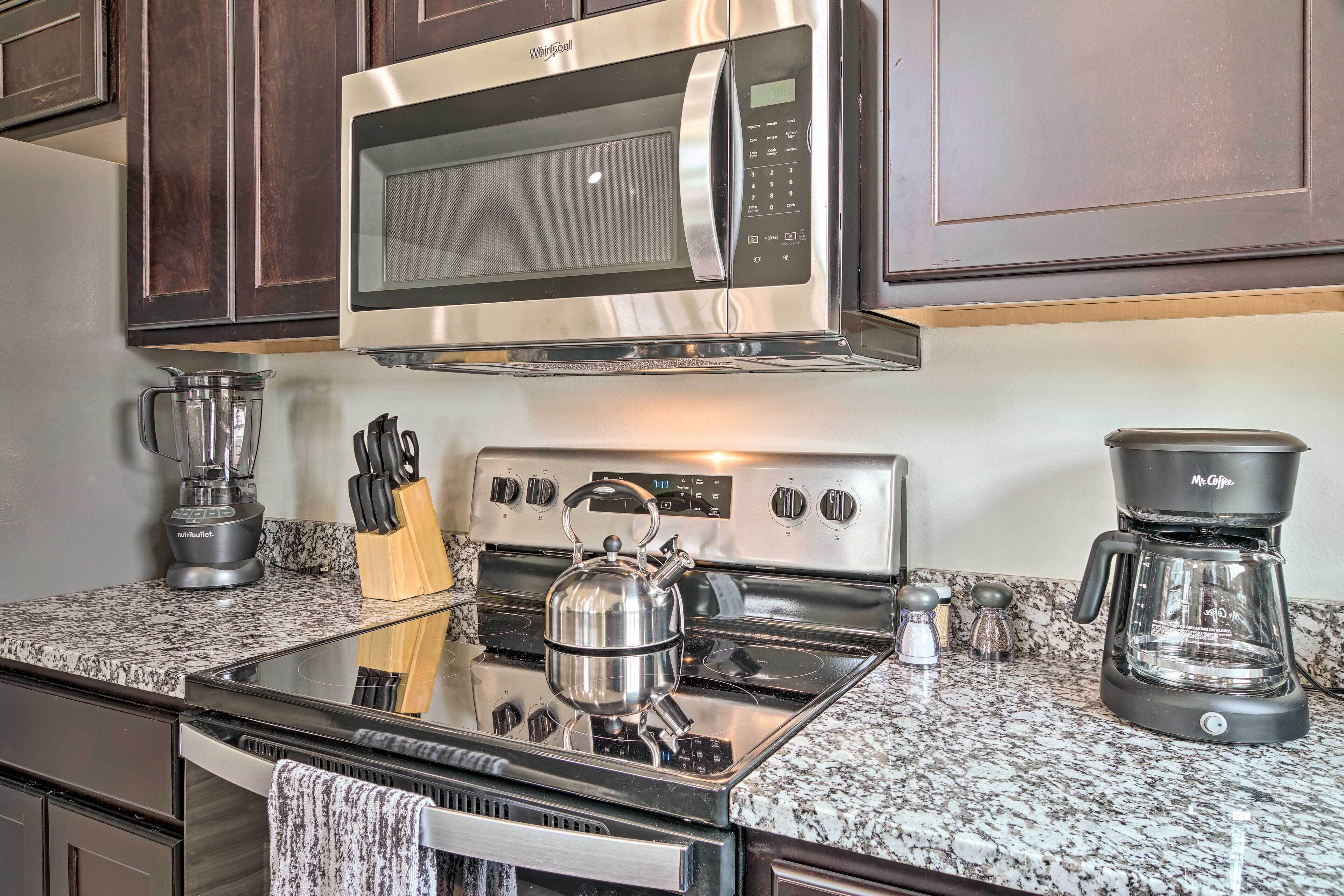 A kitchen with a stainless steel microwave, stove, and coffee maker.