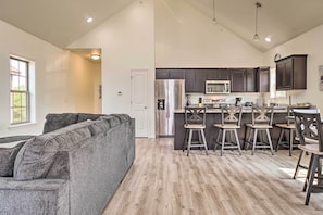 A modern kitchen with dark cabinets, stainless steel appliances, and a bar area with stools.