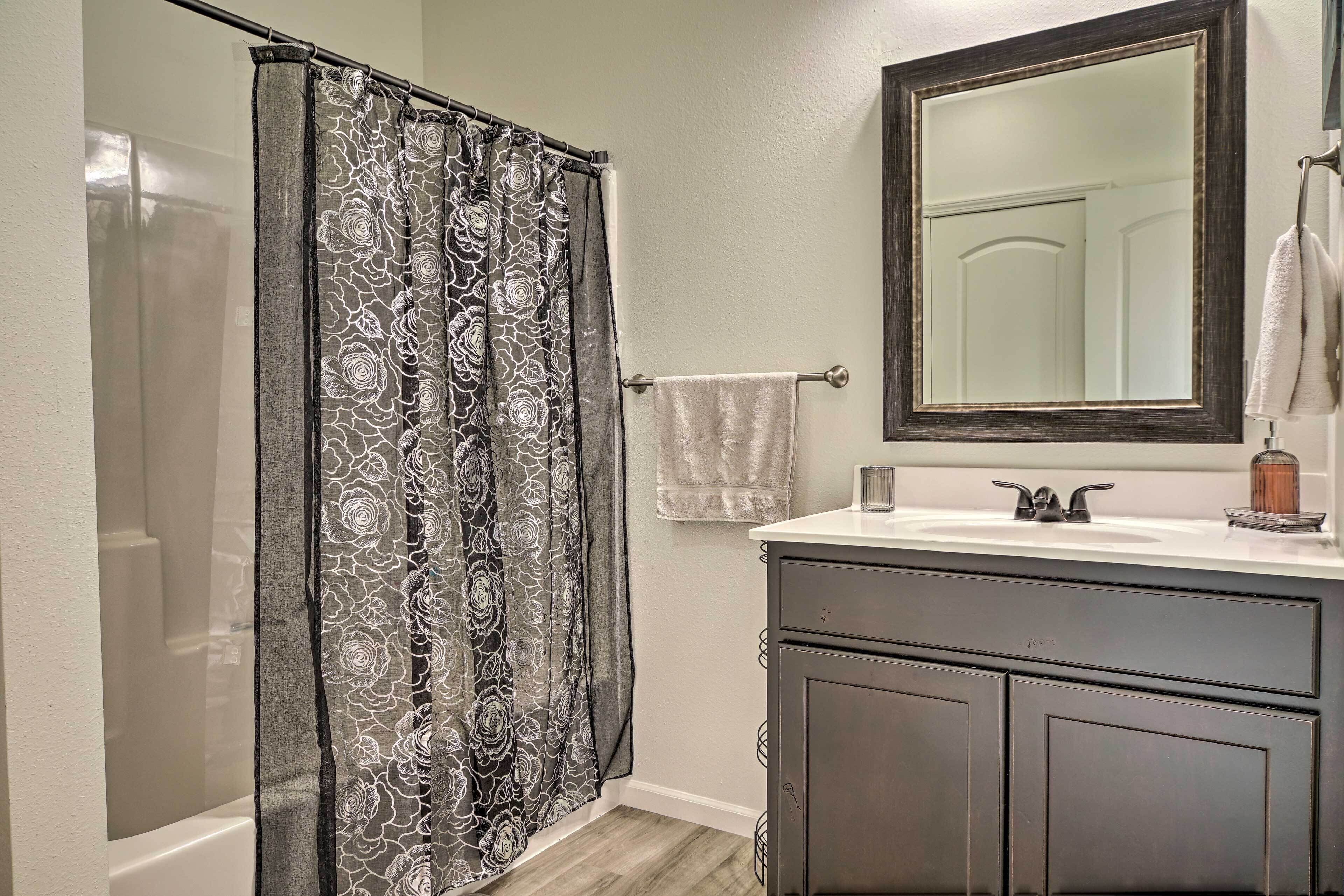 A bathroom with a shower curtain, a towel rack, a mirror, and a sink.