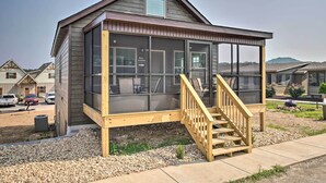 Een gelijkvloers huis met een overdekte veranda en een houten trap naar een terras.