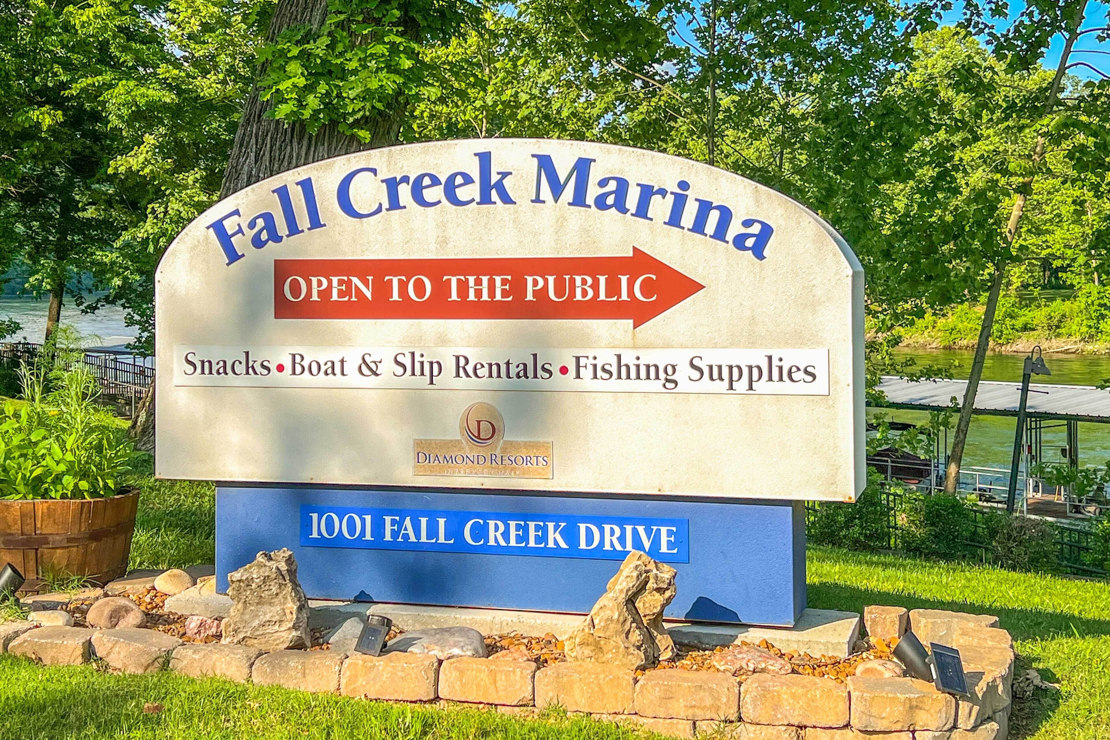 A sign for Fall Creek Marina, indicating it is open to the public and offers amenities like snacks, boat rentals, and fishing supplies.