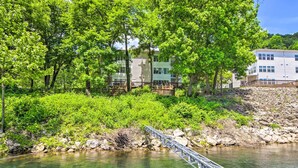 A riverside view with a bridge, lush greenery, and a building with multiple windows.
