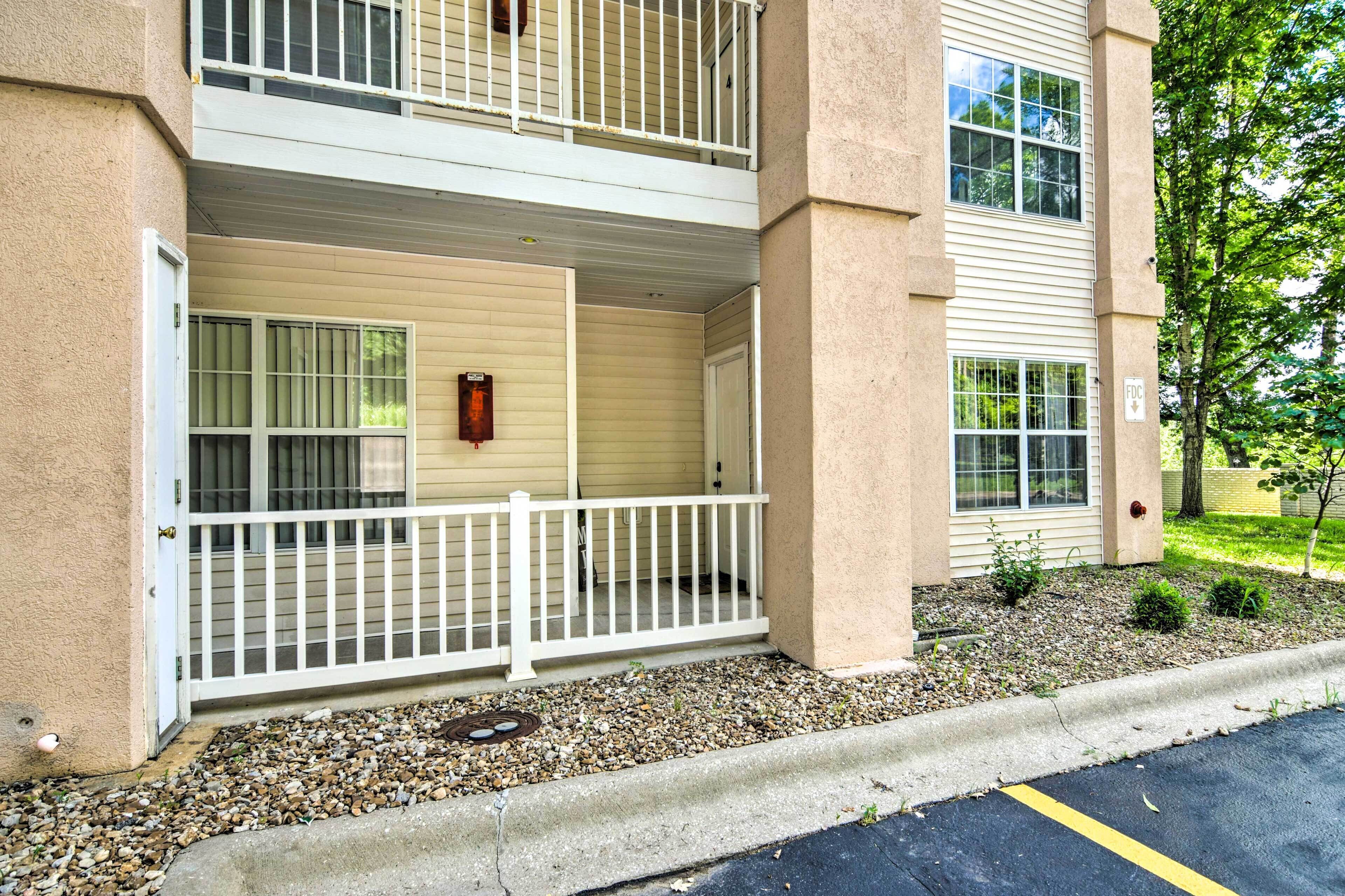 A two-story building with a covered balcony, a gated entrance, and a small garden area.