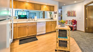 A modern kitchen with wooden cabinets, a dishwasher, and a cart with baskets.