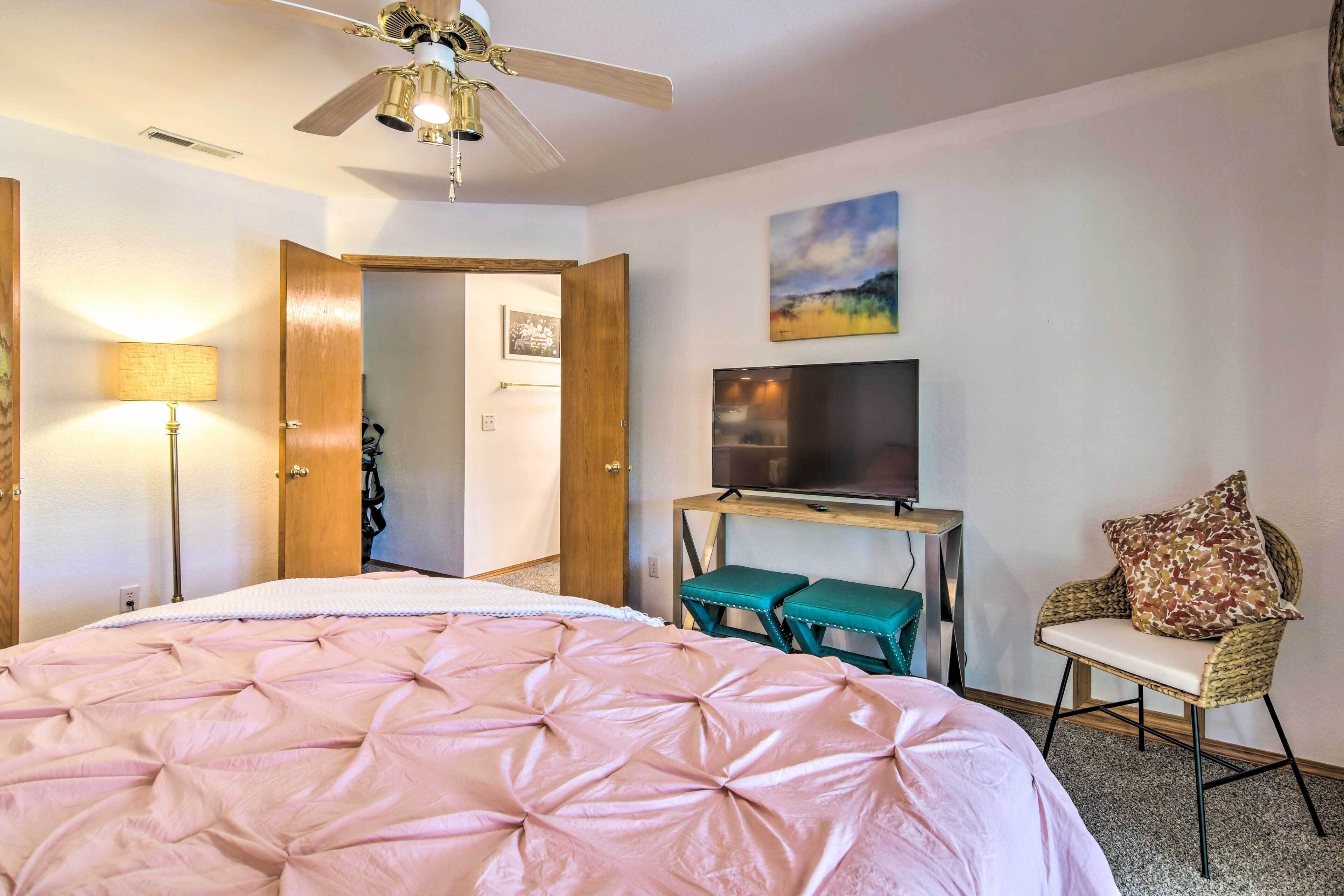 Ein Schlafzimmer mit Bett, Deckenventilator, Fernseher und Stuhl.