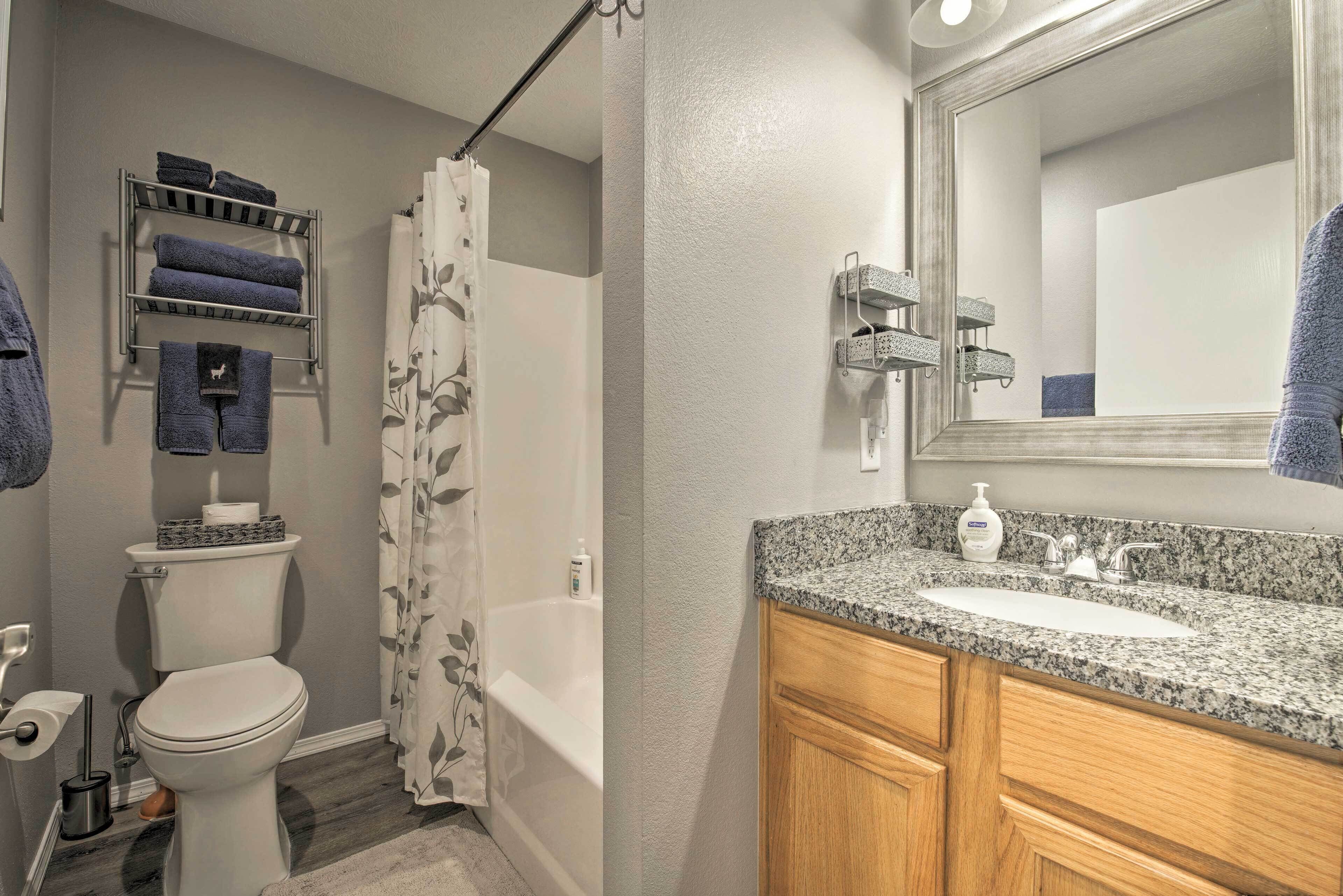 A bathroom with a toilet, sink, and shower. There are towels on a rack and a mirror above the sink.