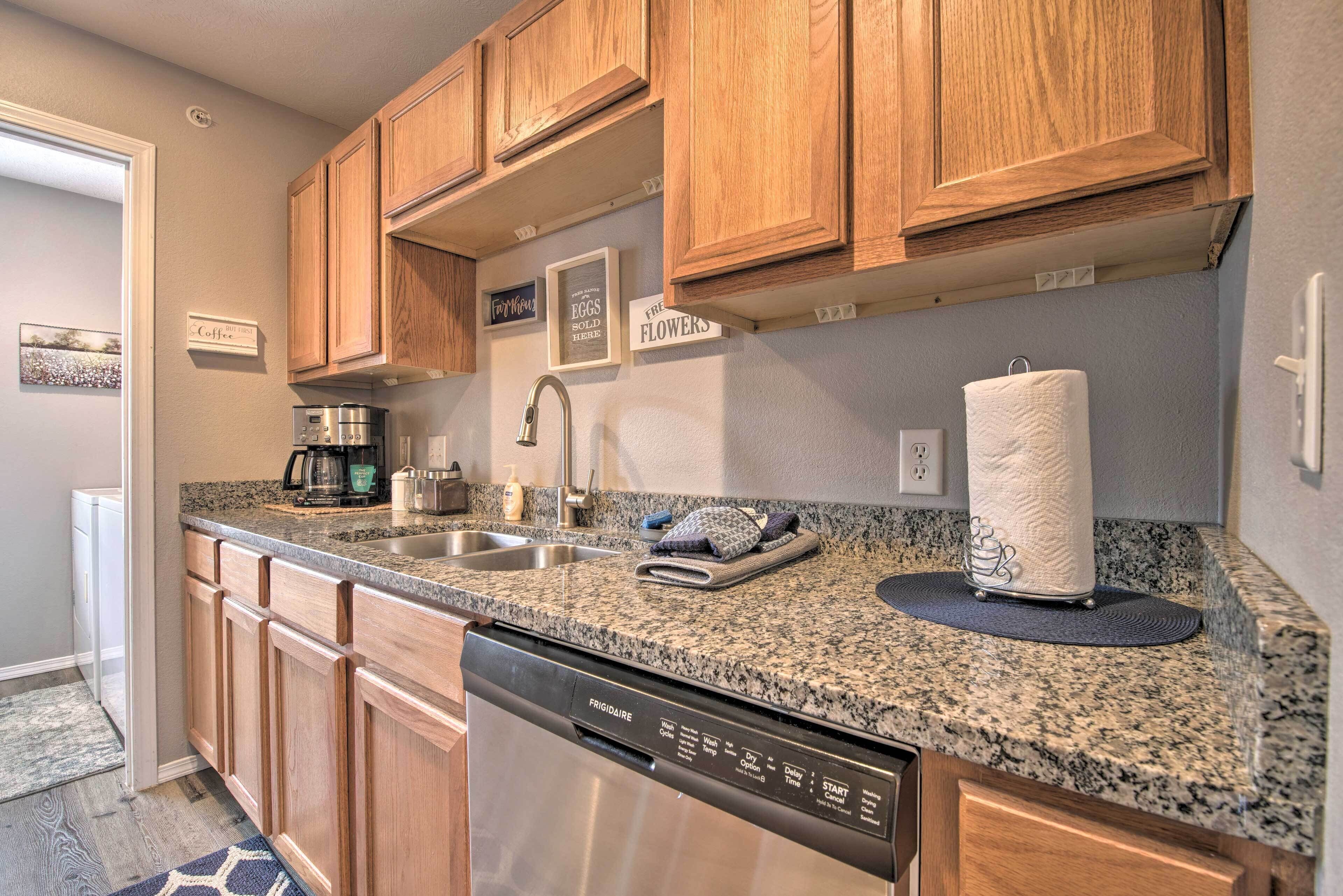 A kitchen with wooden cabinets, granite countertops, a dishwasher, and a coffee maker.