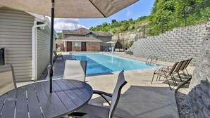 Un jardin avec une piscine, un espace salon extérieur et un mur en briques.