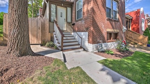 A two-story brick house with a front porch, a wooden fence, and a tree. - 9 Mi to Dtwn: Vibrant St Louis Home! (St. Louis)