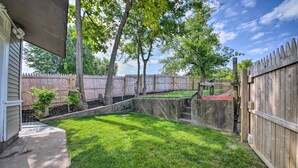 A backyard with a wooden fence, a concrete planter, and a small tree. - 9 Mi to Dtwn: Vibrant St Louis Home! (St. Louis)