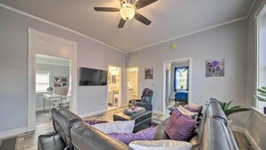 A modern living room with a black leather sofa, a ceiling fan, and a flat-screen TV. - 9 Mi to Dtwn: Vibrant St Louis Home! (St. Louis)