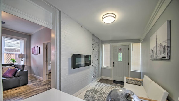 A modern living room with a white sofa, a coffee table, and a TV mounted on the wall. - 9 Mi to Dtwn: Vibrant St Louis Home! (St. Louis)