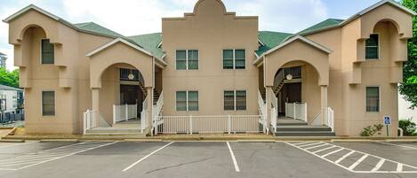 A beige building with a central entrance, two staircases, and a parking lot.