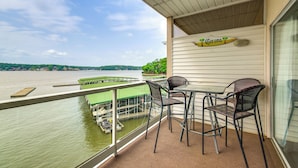 A balcony with a view of a river, two wicker chairs, and a table. - Community Perks! Waterfront Lake Ozark Escape (Lake Ozark)