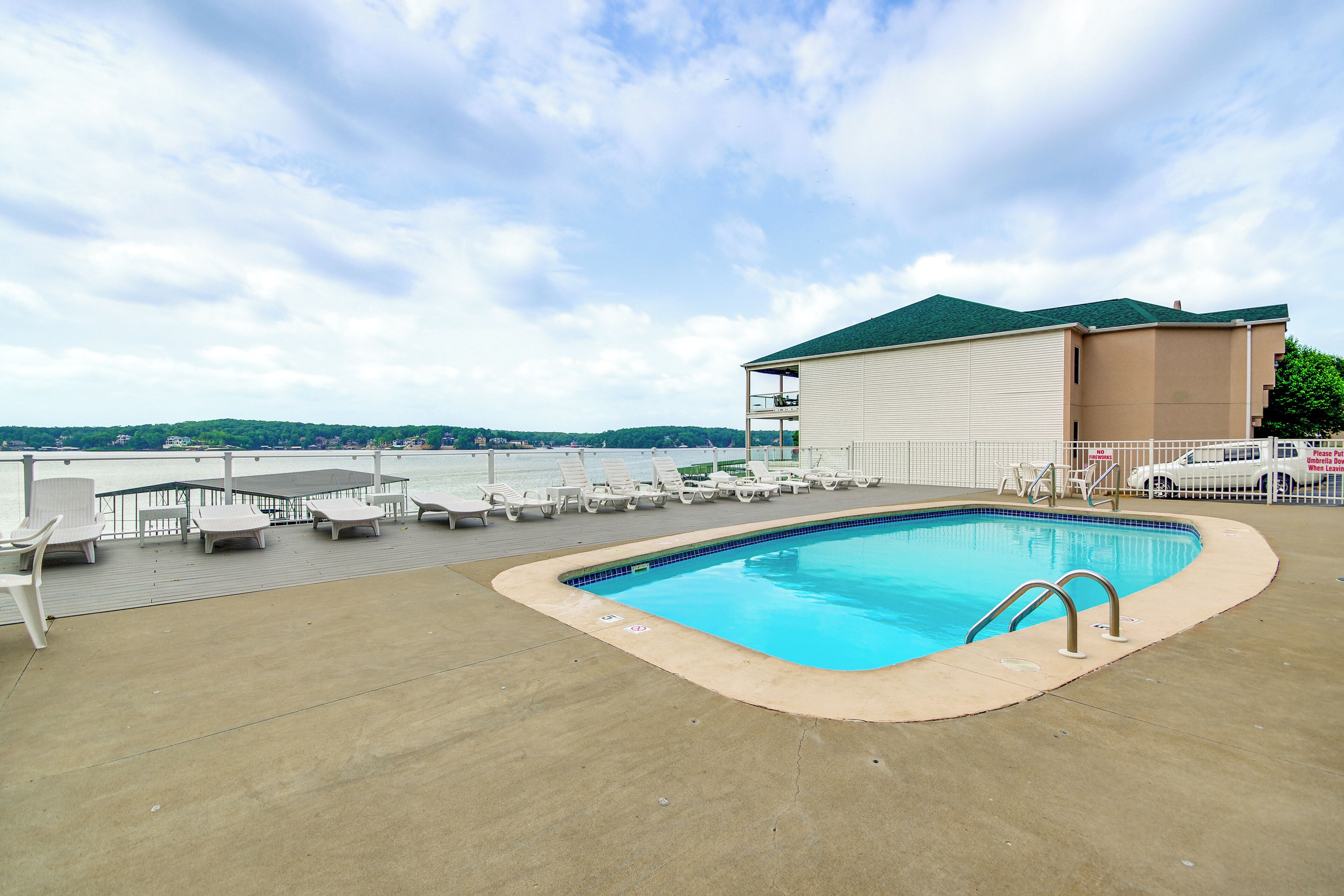 A swimming pool with lounge chairs and a view of the water.