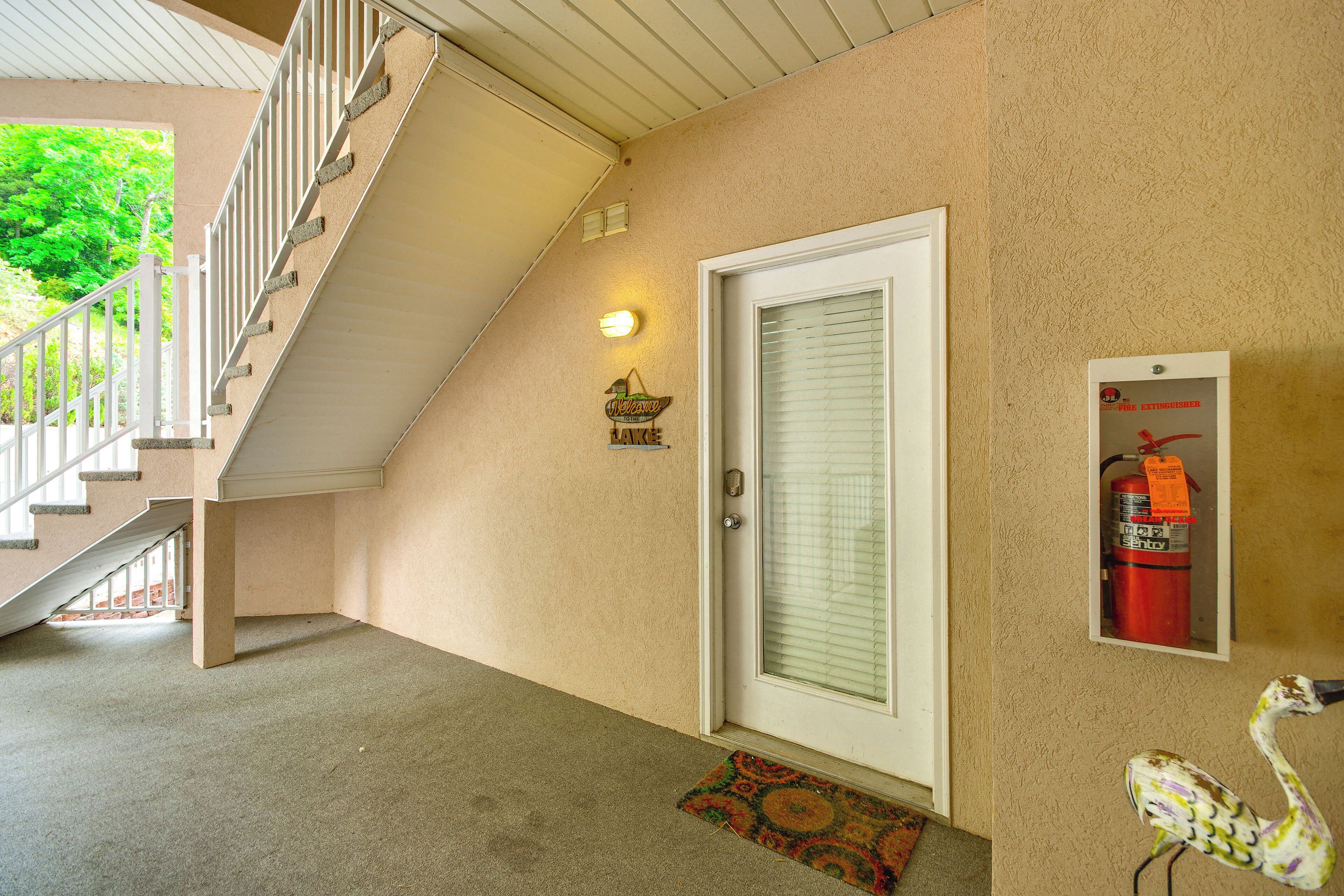 A hotel entrance with a staircase, a door with a glass panel, a fire extinguisher mounted on the wall, and a decorative bird statue.