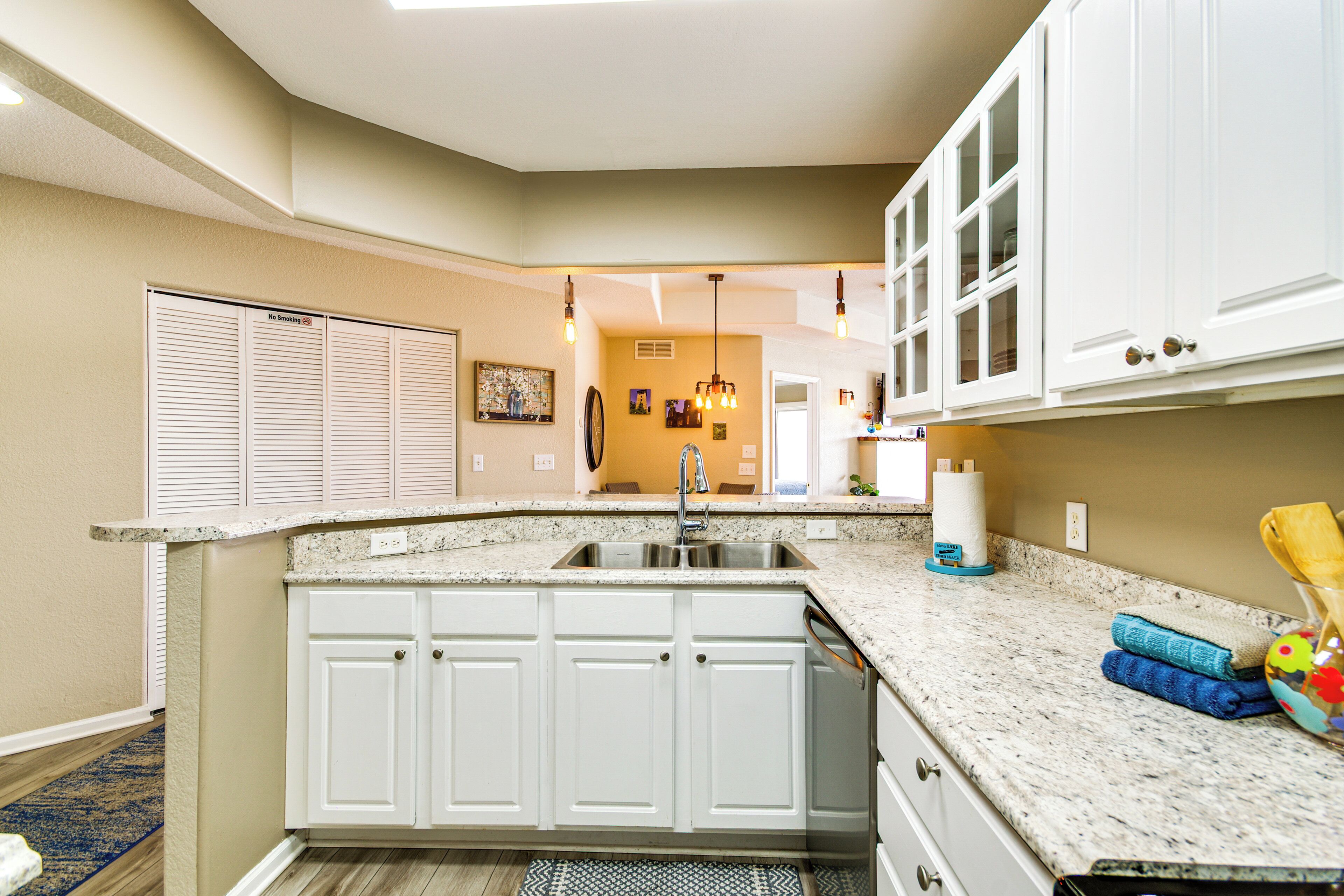 A kitchen with white cabinets, a granite countertop, and a built-in dishwasher.