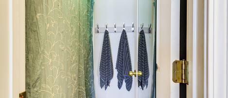 A bathroom with a shower curtain, towel rack, and a door with a brass handle.