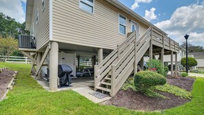 A two-story building with a covered patio area, outdoor seating, and a staircase leading to the upper floor. - Updated Myrtle Beach Cottage w/ Shared Pool! (Myrtle Beach)