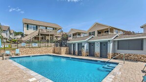 A swimming pool with a brick deck, a covered area with stairs, and a building with a balcony. - Updated Myrtle Beach Cottage w/ Shared Pool! (Myrtle Beach)