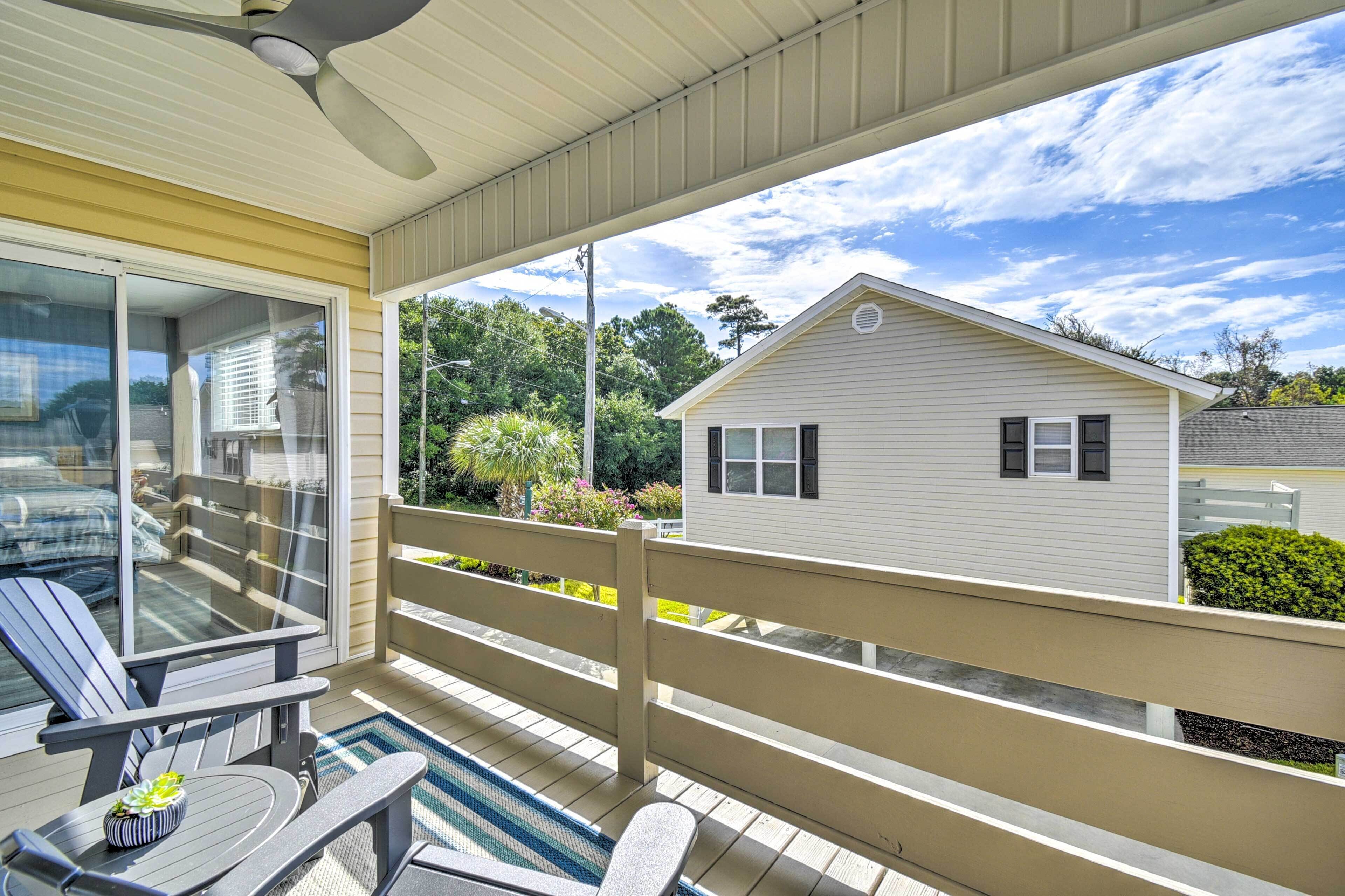 A covered outdoor area with a pool, lounge chairs, and a view of a house.