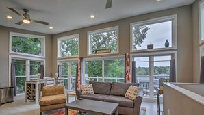 A spacious living room with a sofa, armchair, and coffee table. Large windows provide views of the outdoors. - Waterfront Greenwood Getaway w/ Deck & Grill! (Greenwood)