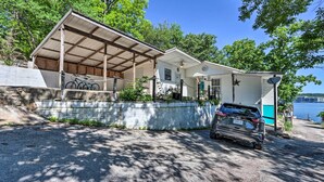 Uma casa de dois andares com varanda coberta, garagem e um carro estacionado na frente.