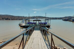 A wooden pier leading to a dock with a covered seating area and a boat.