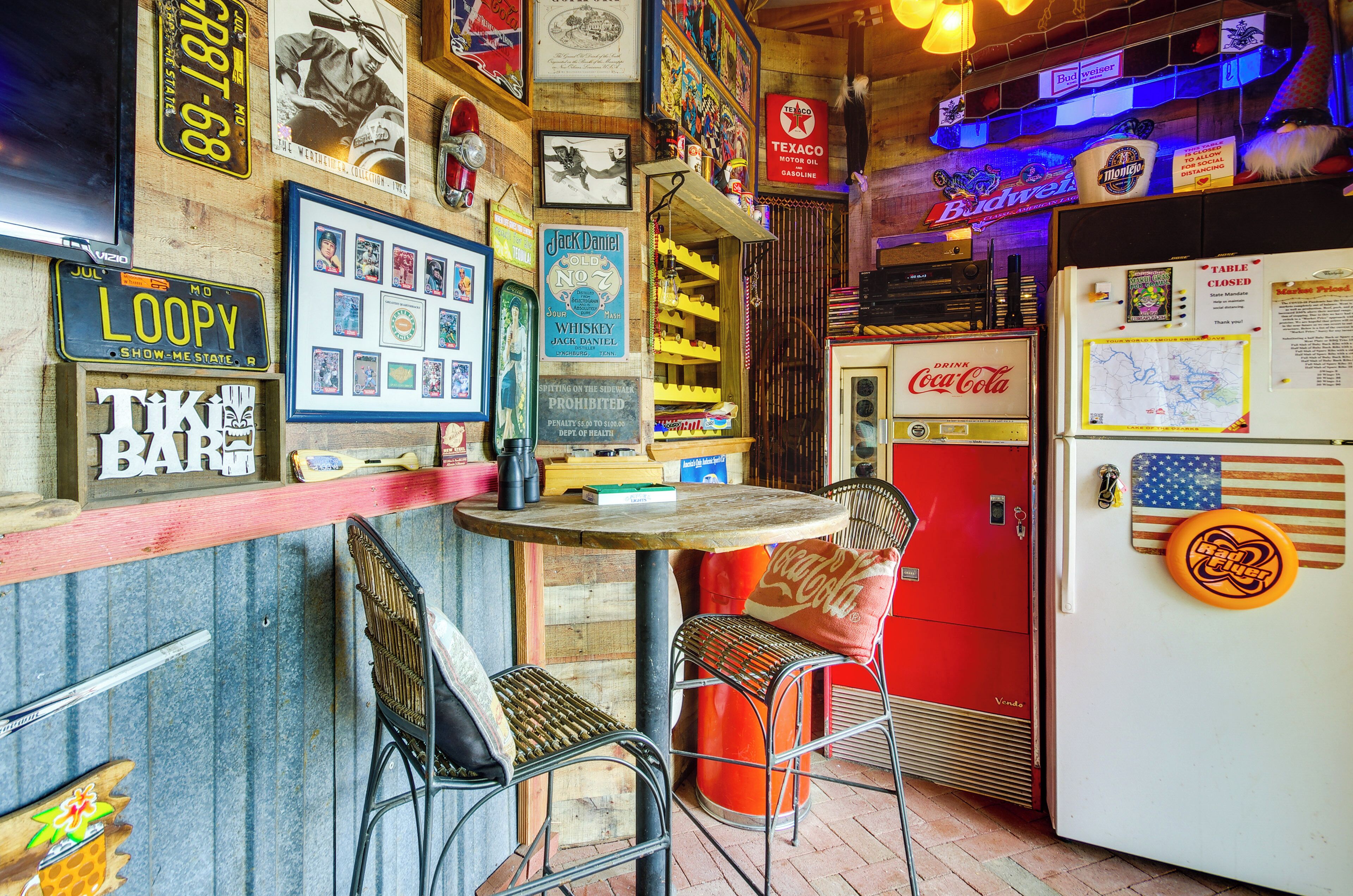 Um bar com temática retrô, decoração vintage, incluindo um frigorífico, banquetes e diversos objetos de coleção nas paredes.
