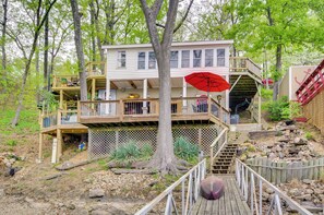 Une maison en bois à plusieurs étages, dotée d’une terrasse et entourée d’arbres.