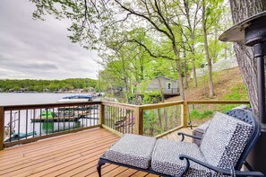 Une terrasse en bois offrant une vue sur un lac, une maison et des bateaux amarrés.