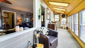 A cozy interior with a wooden ceiling, a sofa, a dining area, and a dog. - Waterfront Ozarks Home w/ Hot Tub, Bar & Dock (Rocky Mount)