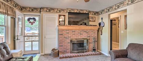 A living room with a fireplace, leather sofas, a ceiling fan, and a door leading outside.