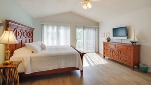 A bedroom with a bed, wooden headboard, a ceiling fan, a dresser, a television, and a window with blinds. - Waterfront Lake of the Ozarks Home w/ Views! (Gravois Mills)